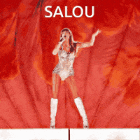 a woman singing into a microphone in front of a red background with the name salou on it
