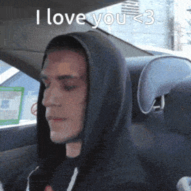 a man in a hooded sweatshirt is sitting in a car with the words i love you < 3 above him