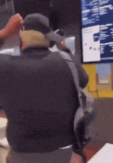a man wearing a hat and a backpack is sitting in front of a monitor