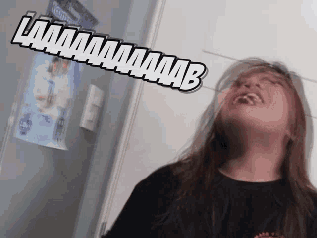a girl is laughing in front of a sign that says laaaaaaaabb