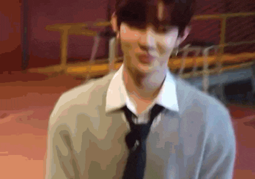 a blurry picture of a man wearing a tie and sweater .