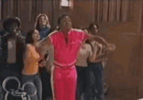 a group of people are standing in a room and dancing .