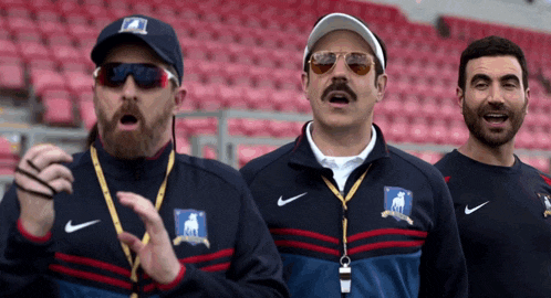 three men are standing in a stadium wearing nike jackets