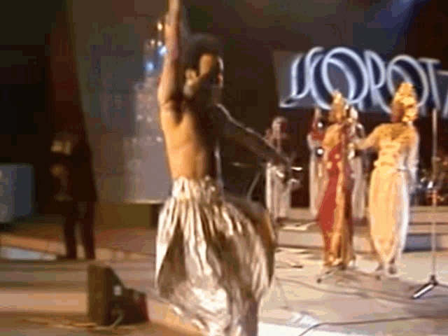 a group of people dancing on a stage in front of a sign that says l' oro