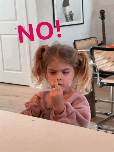 a little girl sitting at a table giving the middle finger with the word no above her