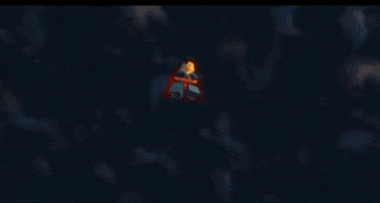 a lego superman with a red cape stands in the dark