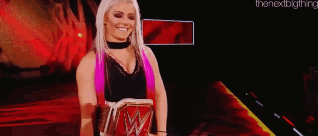 a woman is holding a wrestling championship belt on a stage .