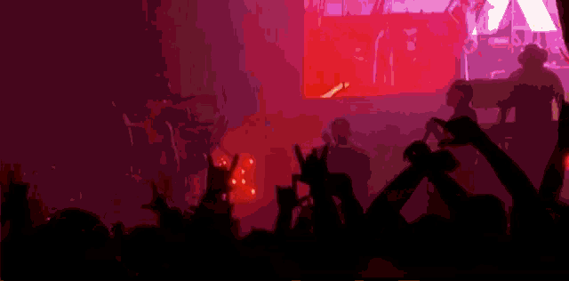 a crowd of people at a concert with their hands up in the air