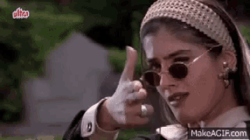 a woman wearing a headband and sunglasses is giving a thumbs up .