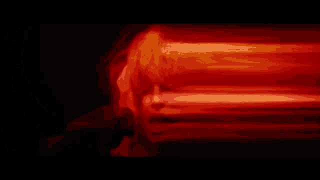 a close up of a person 's face with a red light behind it .