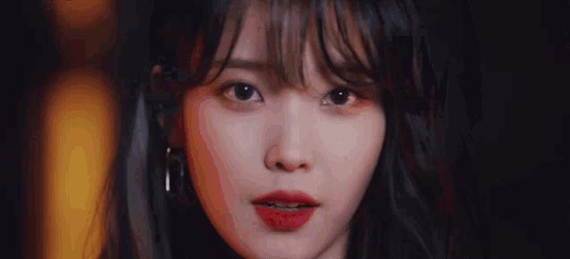 a close up of a woman wearing red lipstick and earrings .