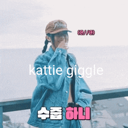 a woman wearing a hat and a denim jacket says katie giggle in a foreign language