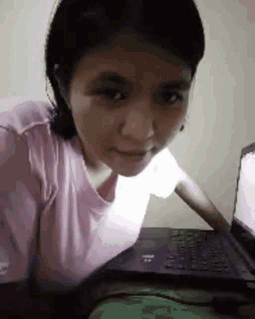 a woman in a pink shirt is sitting in front of a laptop computer