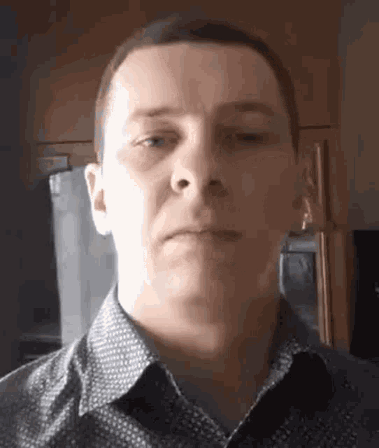 a man in a shirt is making a funny face while looking at the camera .