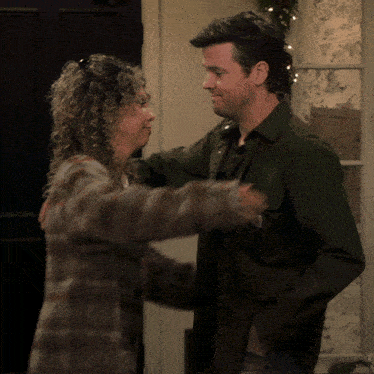 a man and a woman hugging with the man wearing a green shirt that says carhartt