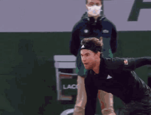 a man wearing a headband is reaching for a tennis ball on a court