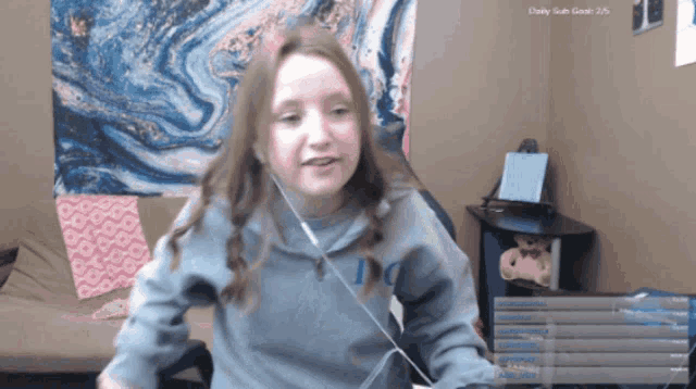 a girl wearing headphones is sitting in front of a screen that says daily subs goal 2/5