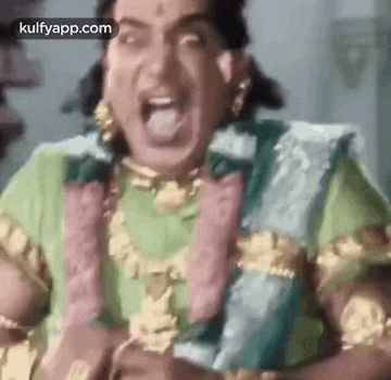 a man in a green and gold costume is making a funny face with his tongue out .