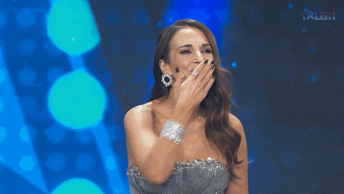 a woman in a silver dress is smiling in front of a sign that says the talent