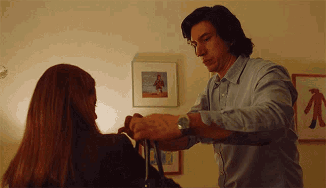 a man adjusts a woman 's purse in front of a framed picture of a man