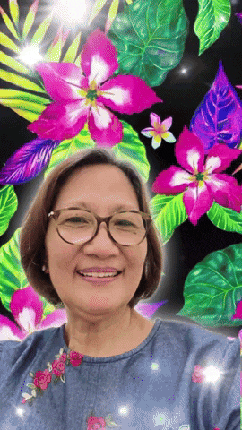 a woman wearing glasses is smiling in front of a colorful background of flowers and leaves