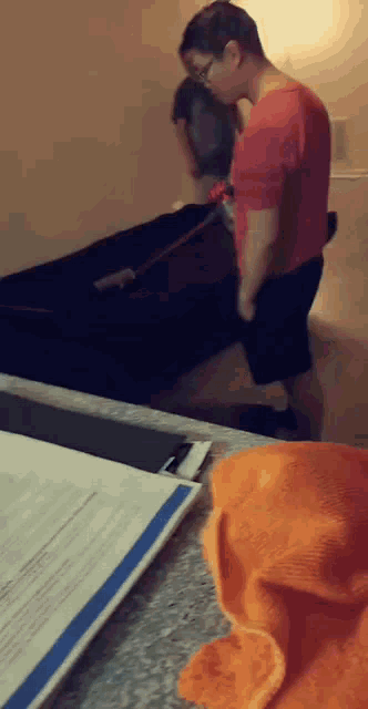 a man in a red shirt is vacuuming a couch in a room