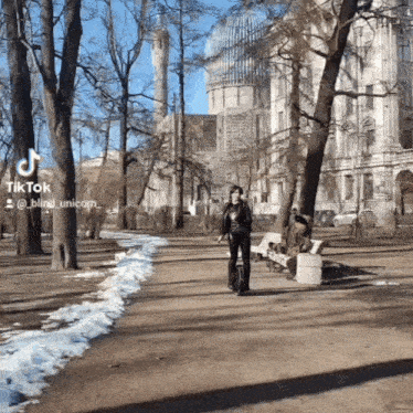 a person riding a scooter in a park with a building behind