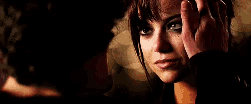 a man is touching a woman 's forehead with his hand in a dark room .