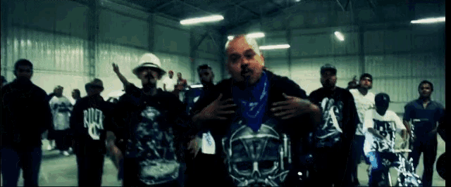 a man wearing a blue bandana with a skull on it stands in front of a crowd