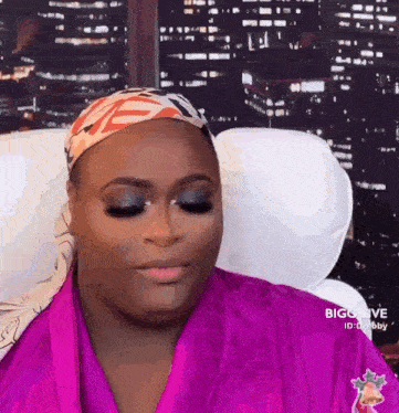a woman wearing a purple robe and a head scarf is sitting in a chair .