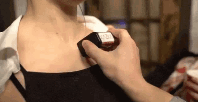 a person is applying nail polish to a woman 's neck .