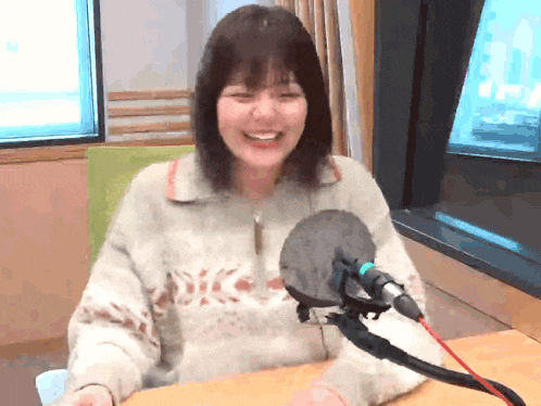 a woman is smiling in front of a microphone in a room