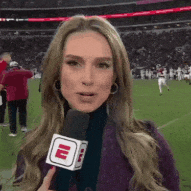 a woman is holding a microphone with a letter e on it .