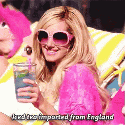 a woman in sunglasses holds a glass of iced tea