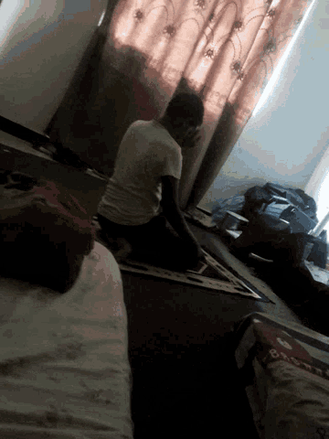 a man is sitting on a rug in a dark room with a blanket that says ' a ' on it