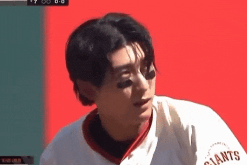 a baseball player wearing a giants jersey looks at something