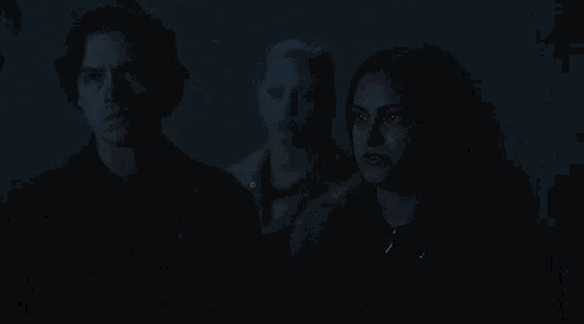 a man and two women are standing next to each other in the dark .