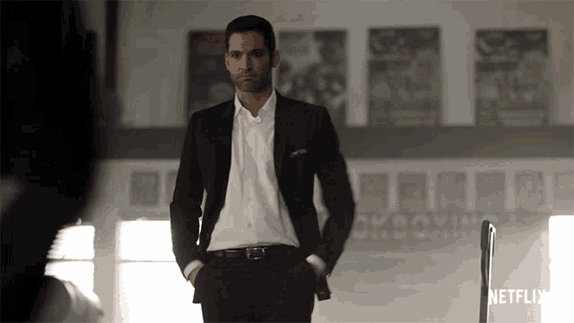 a man in a suit stands in front of a sign that says netflix on it