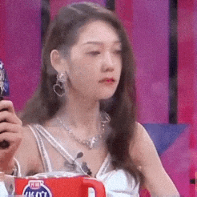 a woman is sitting in front of a cup that says pepsi