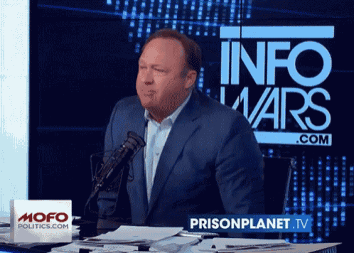 a man stands in front of a screen that says info wars.com