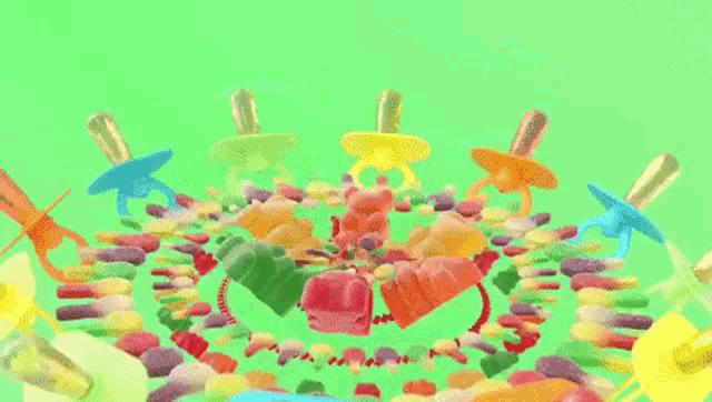 gummy bears and pacifiers are surrounded by candy on a green background