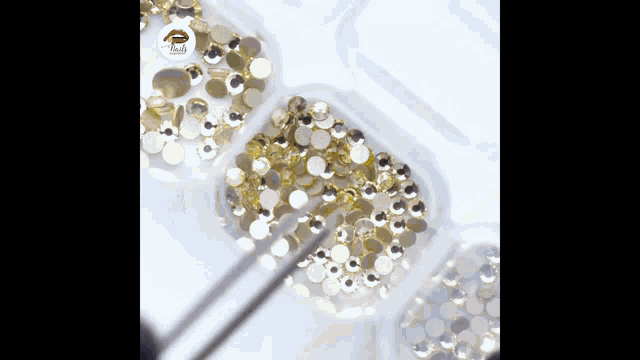 a box of gold and silver rhinestones with a lipstick logo on the bottom