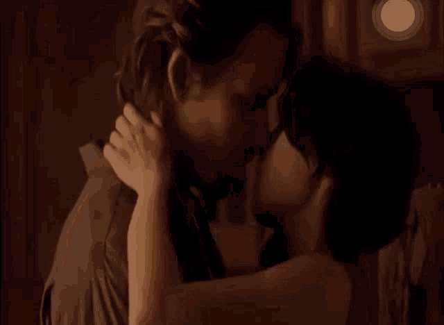 a man and a woman are kissing on a bed in a dark room .