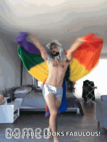 a shirtless man is dancing with a rainbow flag behind him and the words new table looks fabulous