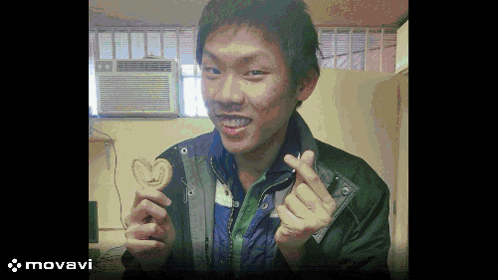 a man in a black jacket holds a heart shaped cookie in his hand