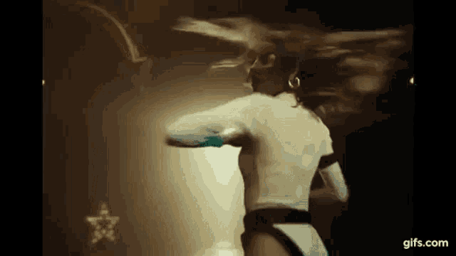 a woman in a white dress is dancing in a dark room .