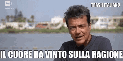 a man is sitting in front of a body of water with a caption that says trash italiano