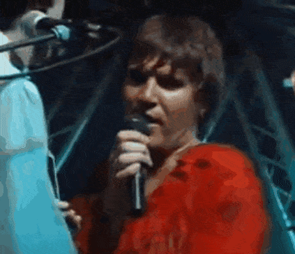 a man in a red shirt is singing into a microphone ..