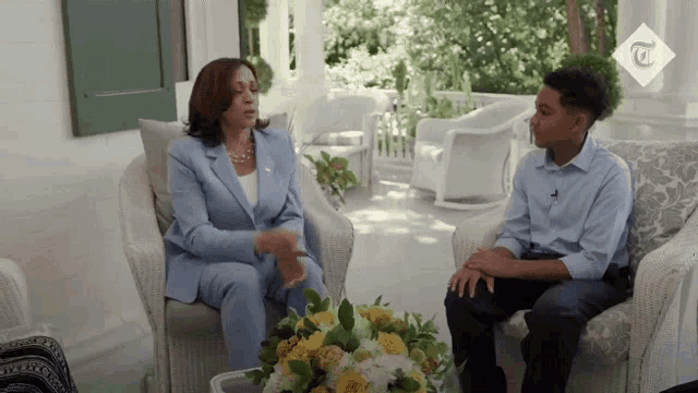 a woman in a blue suit sits next to a boy in a blue shirt on a porch