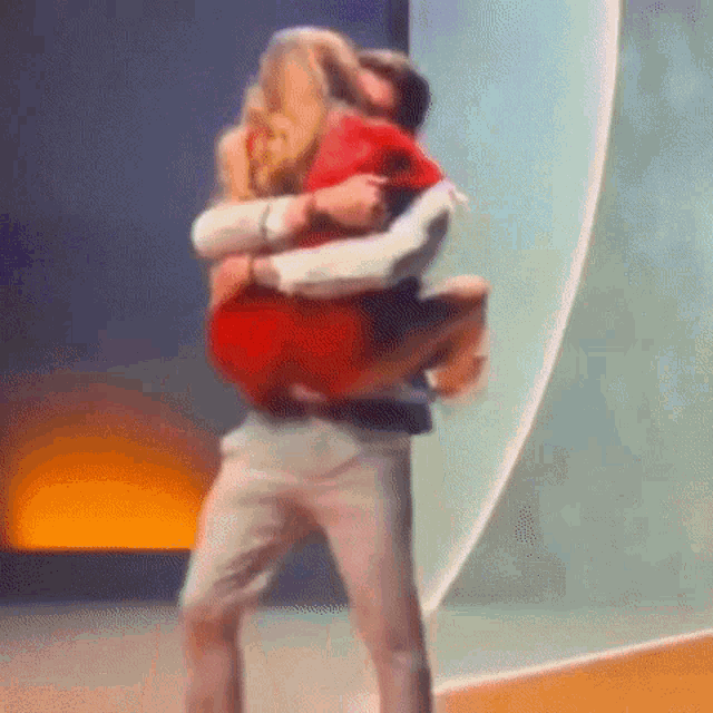 a man is carrying a woman in his arms on a stage and kissing her .